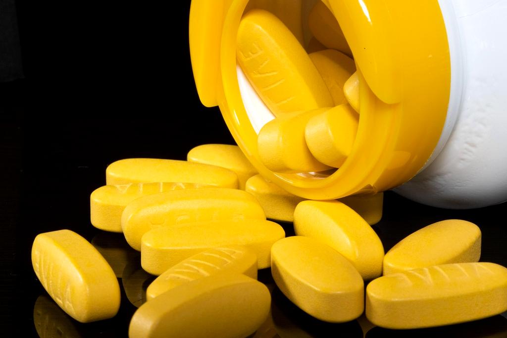 Bottle of daily multivitamin capsules on a wooden table